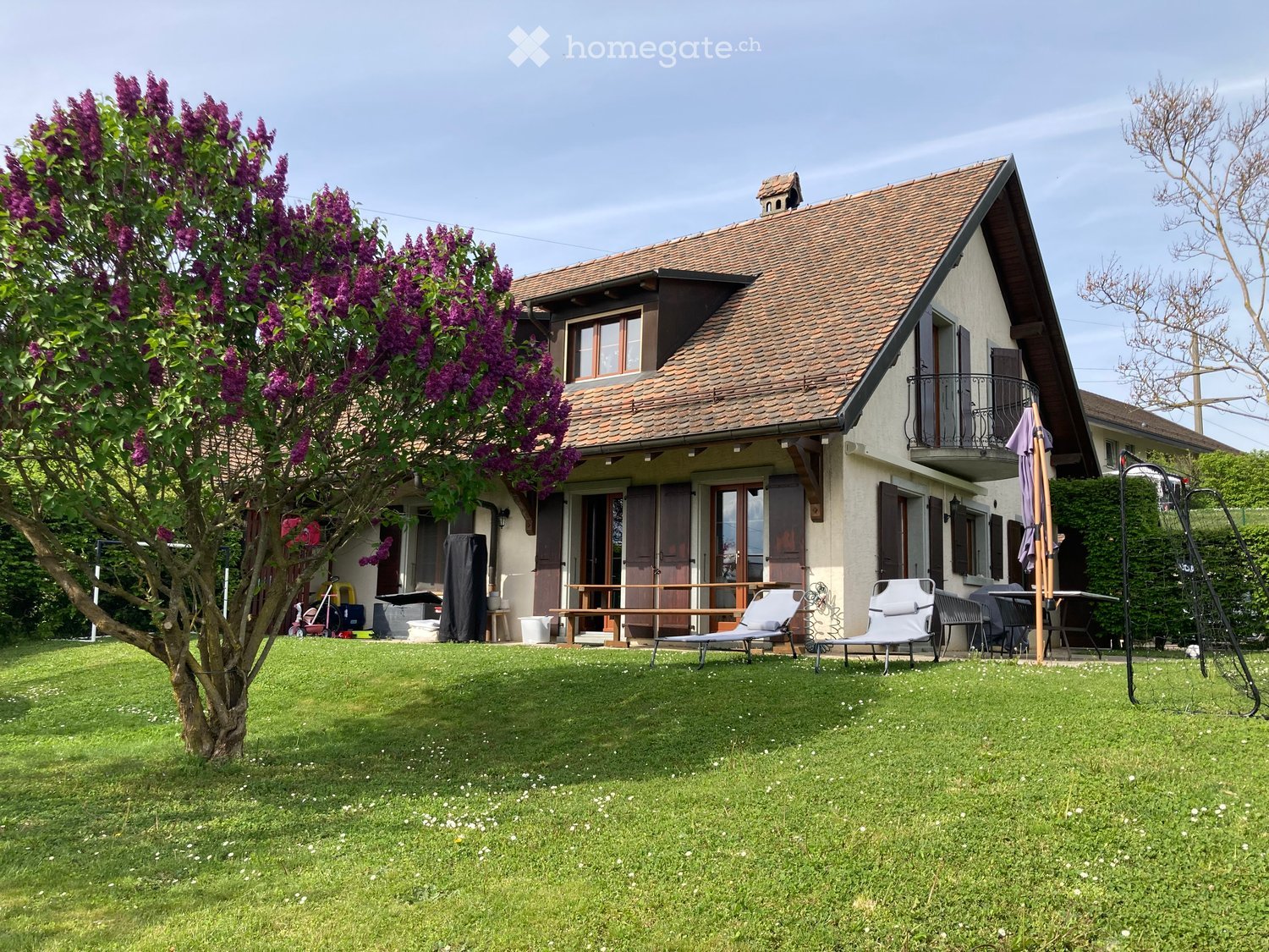 Detached house, brown roof, white walls, balcony, garden, outdoor furniture