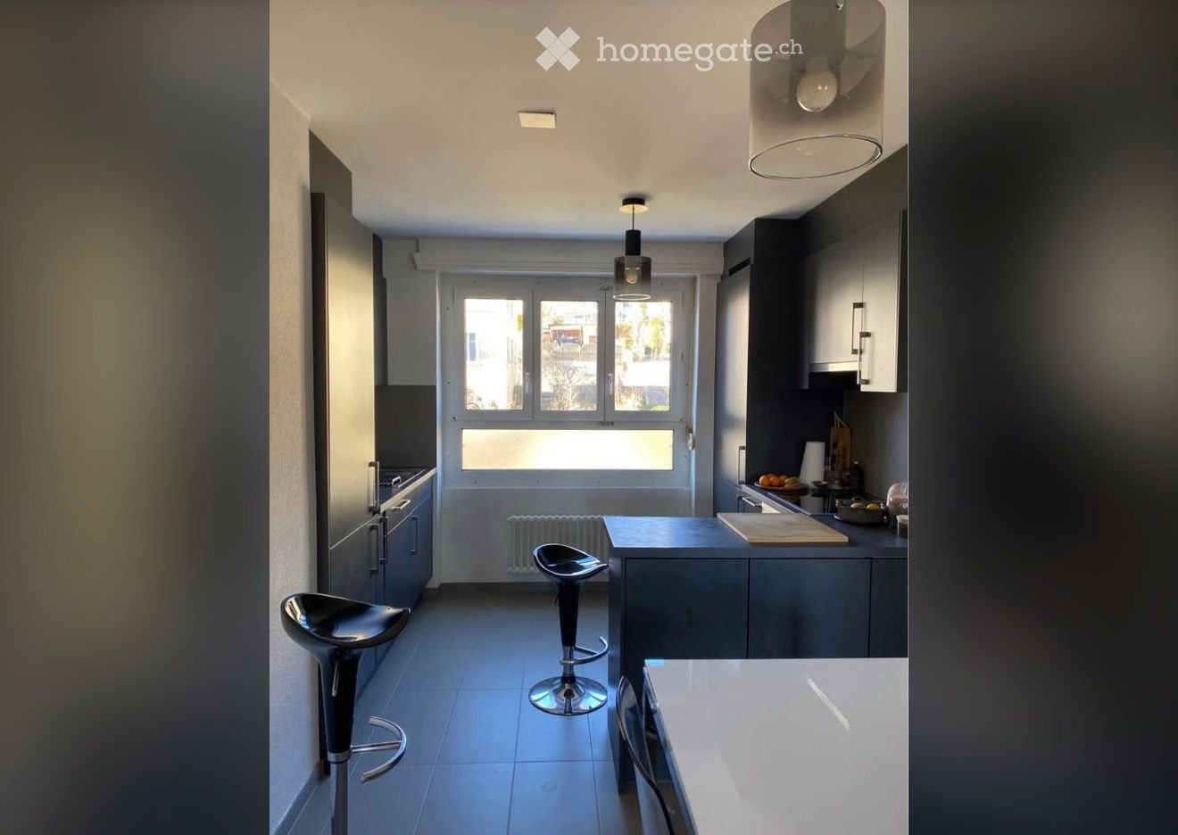 modern kitchen with black cabinets, white countertops, two stools, large windows, ceiling lamps
