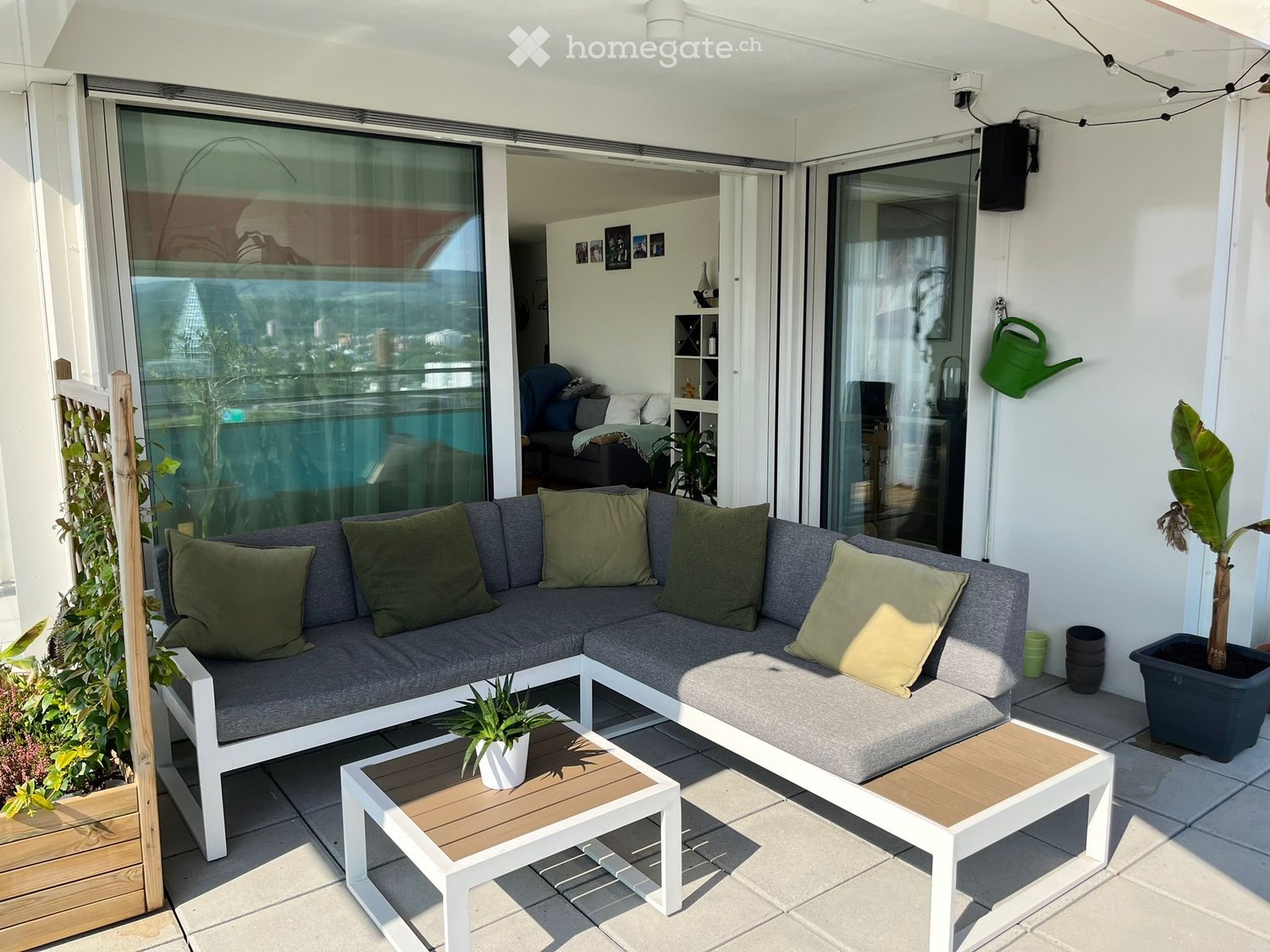 modern L-shaped sofa, wooden coffee tables, potted plants, sliding glass doors, balcony, view of the city