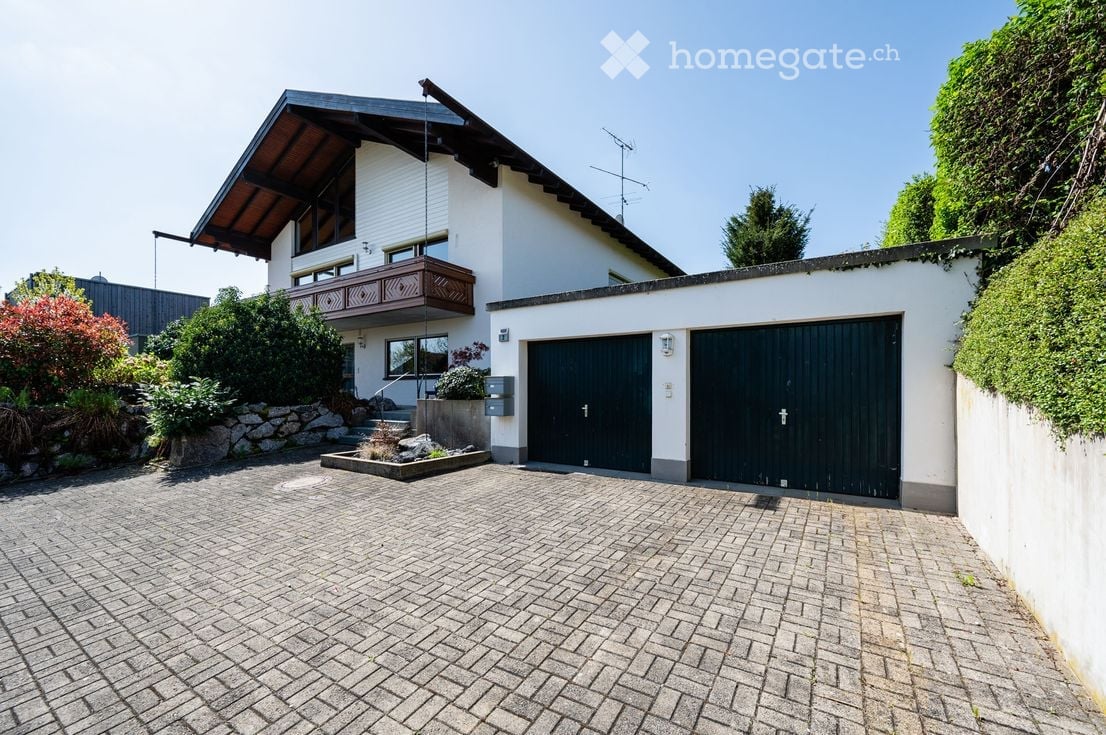 2 story house, white exterior, brown roof, 2 garages, brick driveway