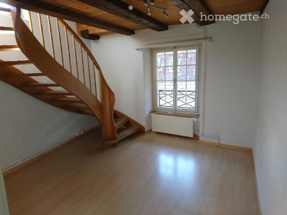 empty room with wooden staircase and window with balcony