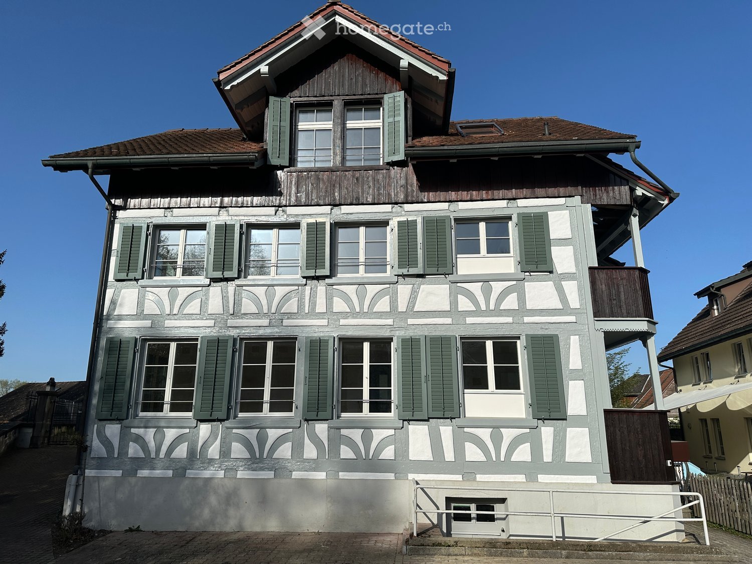 3 story house, wooden and white exterior, green shutters, balconies