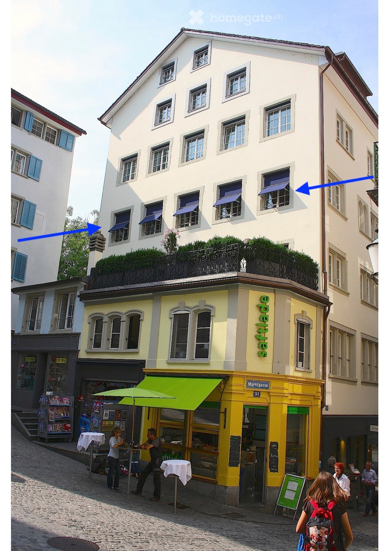 Other. {"visible_features":[],""type""":""Building"",""objects""":[],"""description""":""A multi-story building with a yellow storefront on the ground floor and a green awning. The upper floors have white walls and multiple windows with blue shutters. The