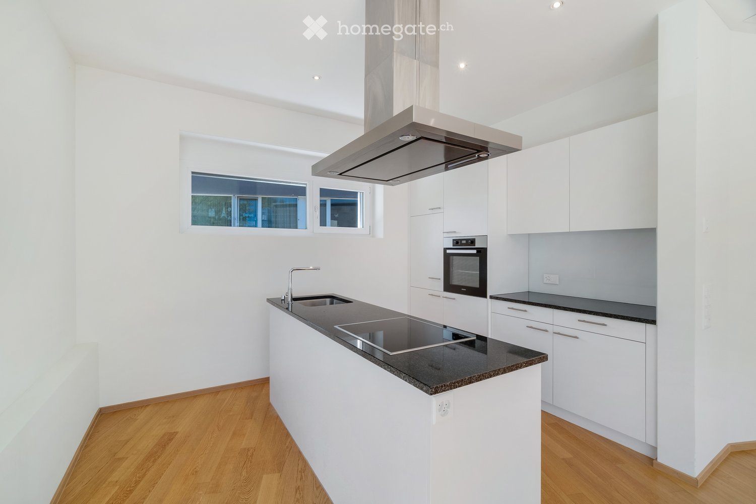 modern kitchen with white cabinets, black granite countertops, induction cooktop, stainless steel extractor hood, built-in oven, sink with faucet, wooden floor
