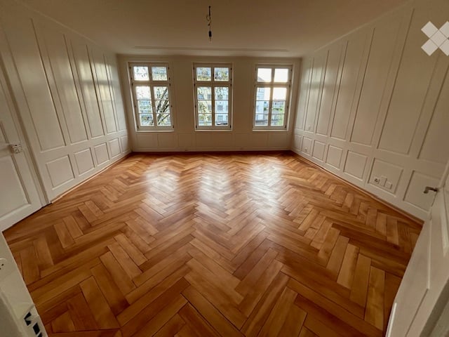 empty room, wooden parquet floor, white walls, three windows, wooden doors
