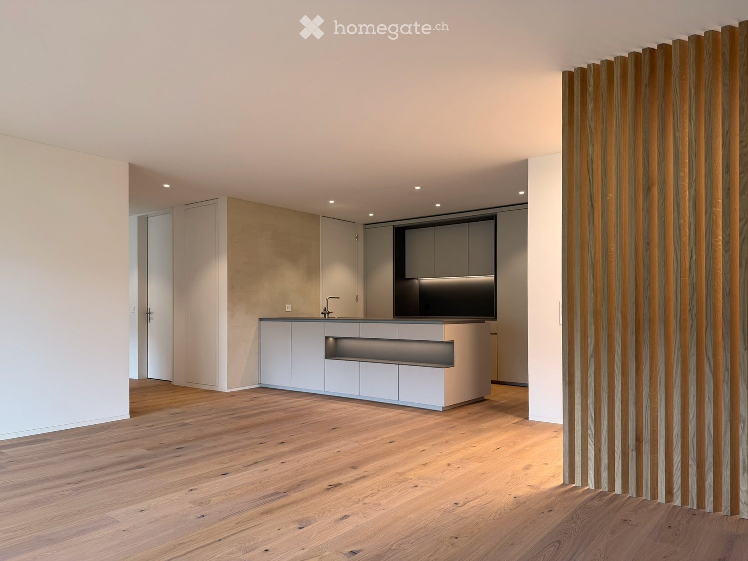 Modern kitchen with a kitchen island, white cabinets, and a sink with a faucet. The countertop has built-in lighting.