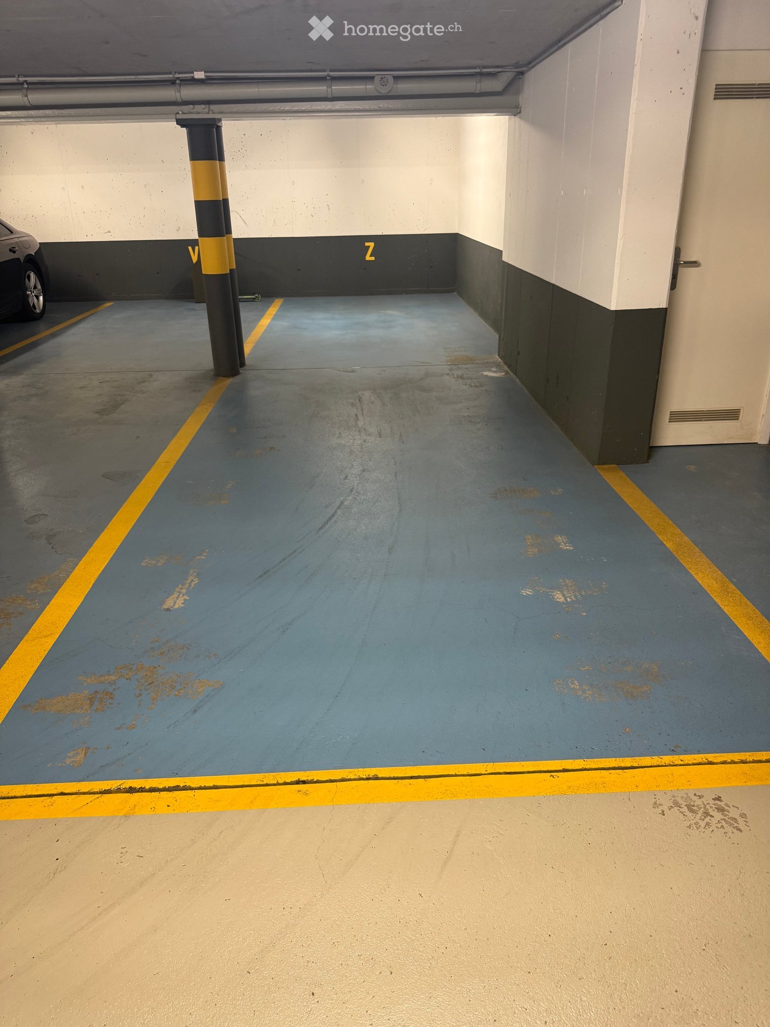 Other. {"visible_features": ["Parking place"], "type": "Garage", "objects": [], "description": "Empty parking space with yellow and white markings, a pillar, and a car parked at the end.", "localized_descriptions": {"EN": "Empty parking space with yellow