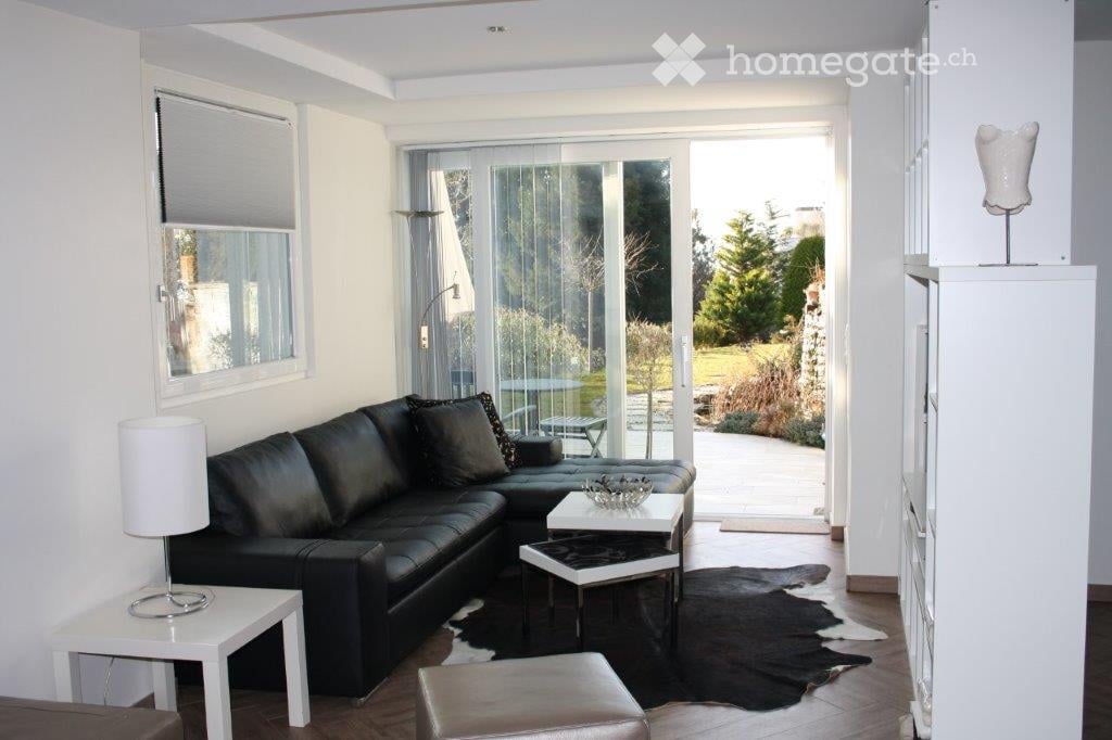 black leather sofa, white coffee tables, white lamp, white walls, wooden floor, sliding glass doors, outdoor patio, garden view