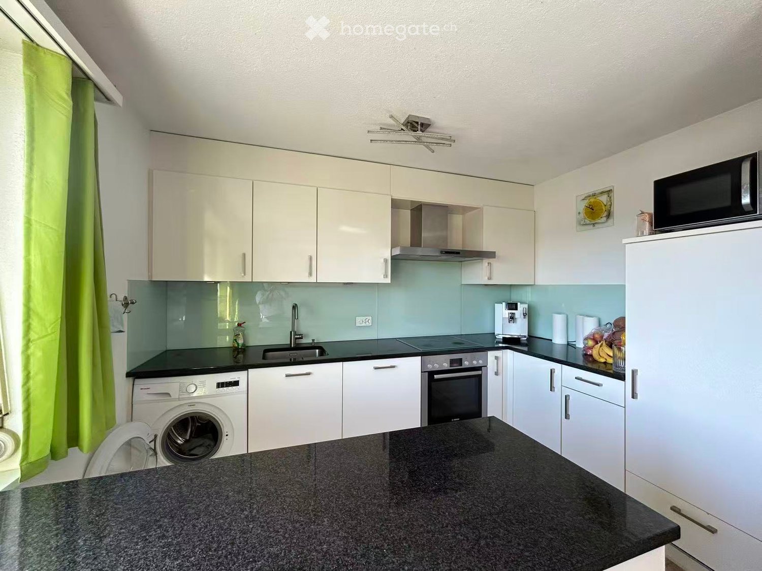 Kitchen. Modern kitchen with white cabinets, black countertops, stainless steel appliances, and a central island.