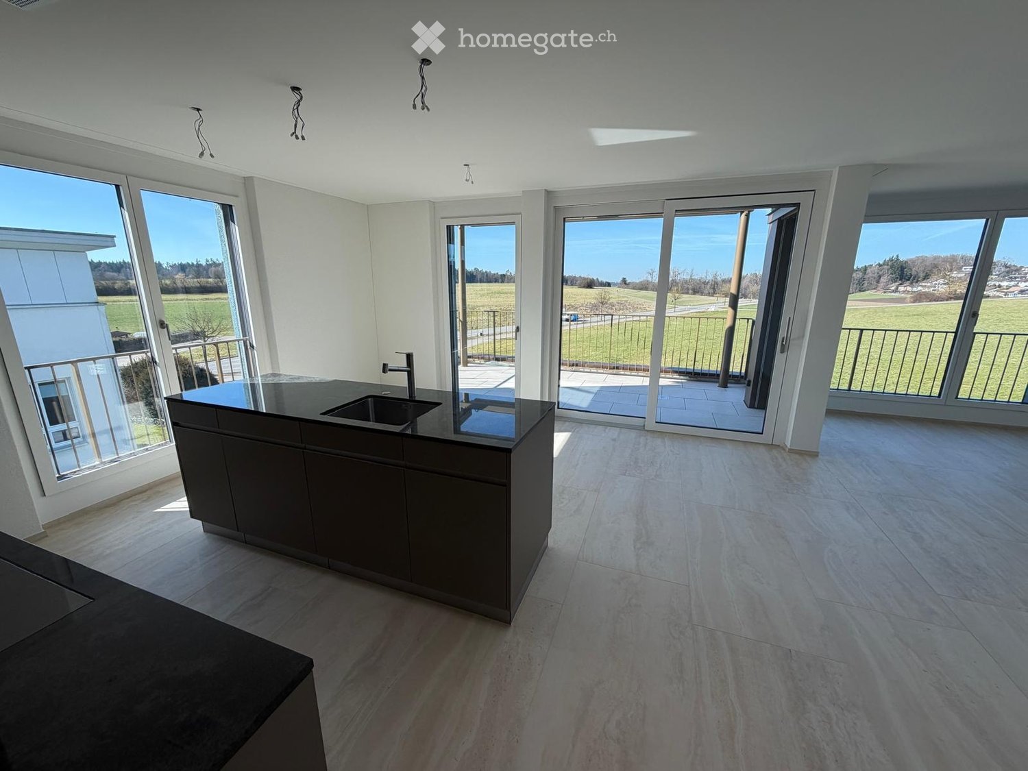 Modern kitchen with large windows, balcony, and a view of the countryside.