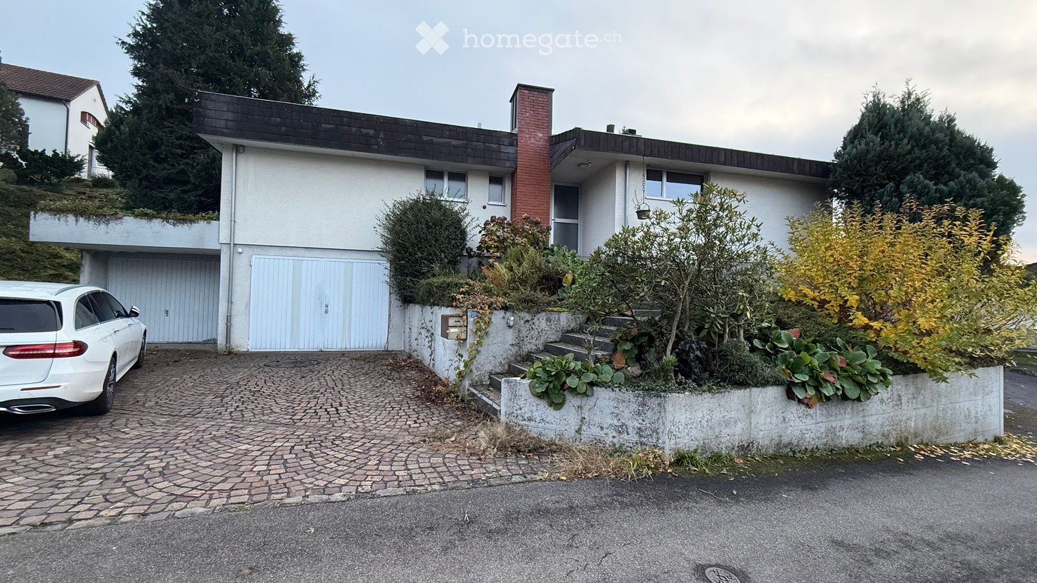 white and red brick house, 2 garages, driveway, plants, garden