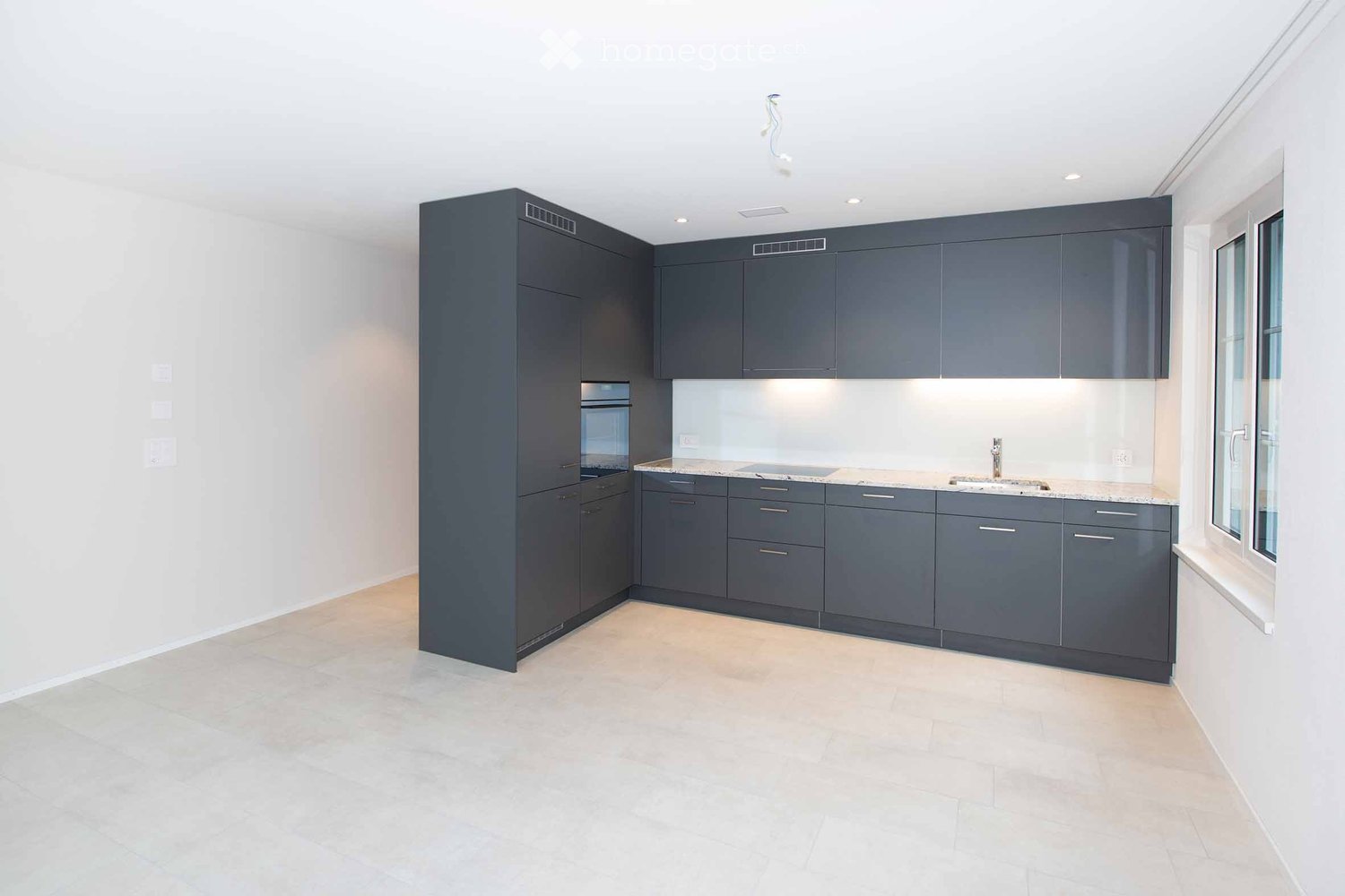 empty modern kitchen with white tile floors, gray cabinetry, and granite countertops, under cabinet lighting