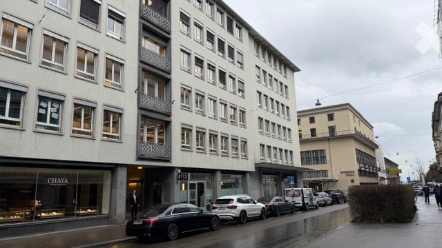 multi-story building, multiple windows, parking on street, commercial ground floor