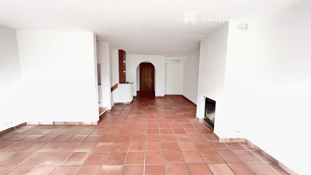 Empty room with white walls, red tiled floor, and a fireplace on the right wall.