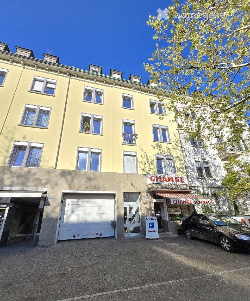 Four-story building with yellow facade, multiple windows, garage entrance, and signage for 'CHANGE' and 'CHANGE SCHNEGG'.