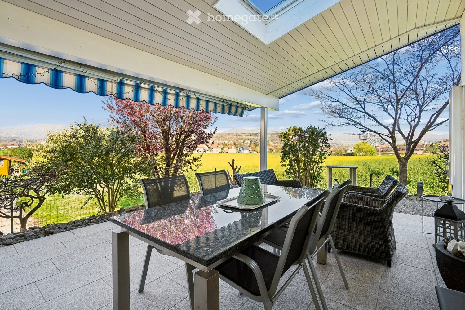 Outdoor dining area with a granite table, chairs, and a view of a field.