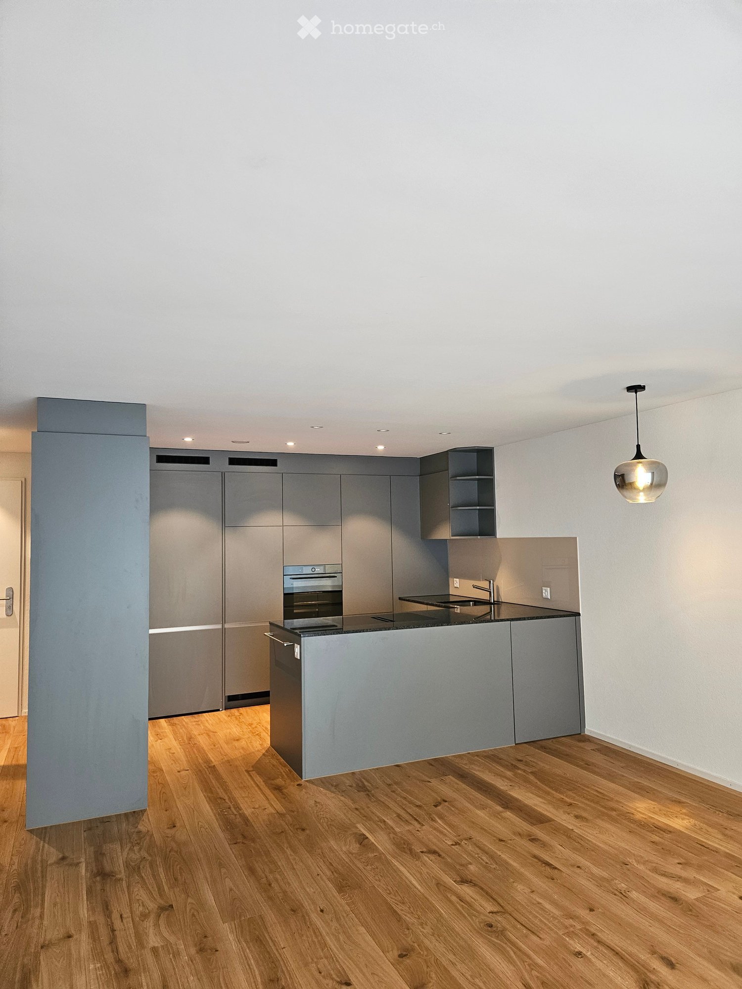 Kitchen. Modern kitchen with grey cabinets, wooden flooring, and a central island with an oven and sink.