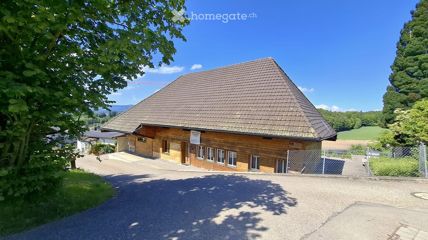 House. Single-story wooden house with a pitched roof, multiple windows, and a gravel driveway.