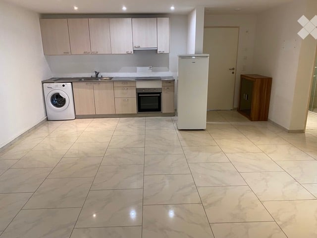 empty kitchen with refrigerator, sink, stove, and washing machine, tiled floor, wooden cabinets