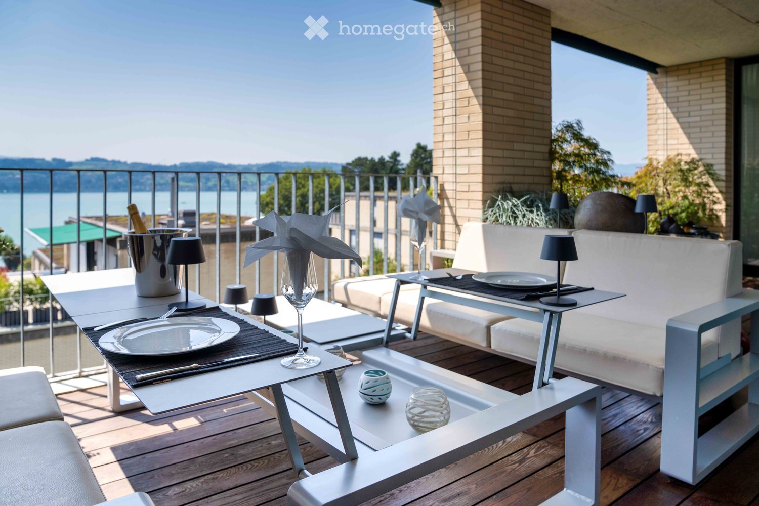 Balcony area with wooden floor, table, couch, views of the water