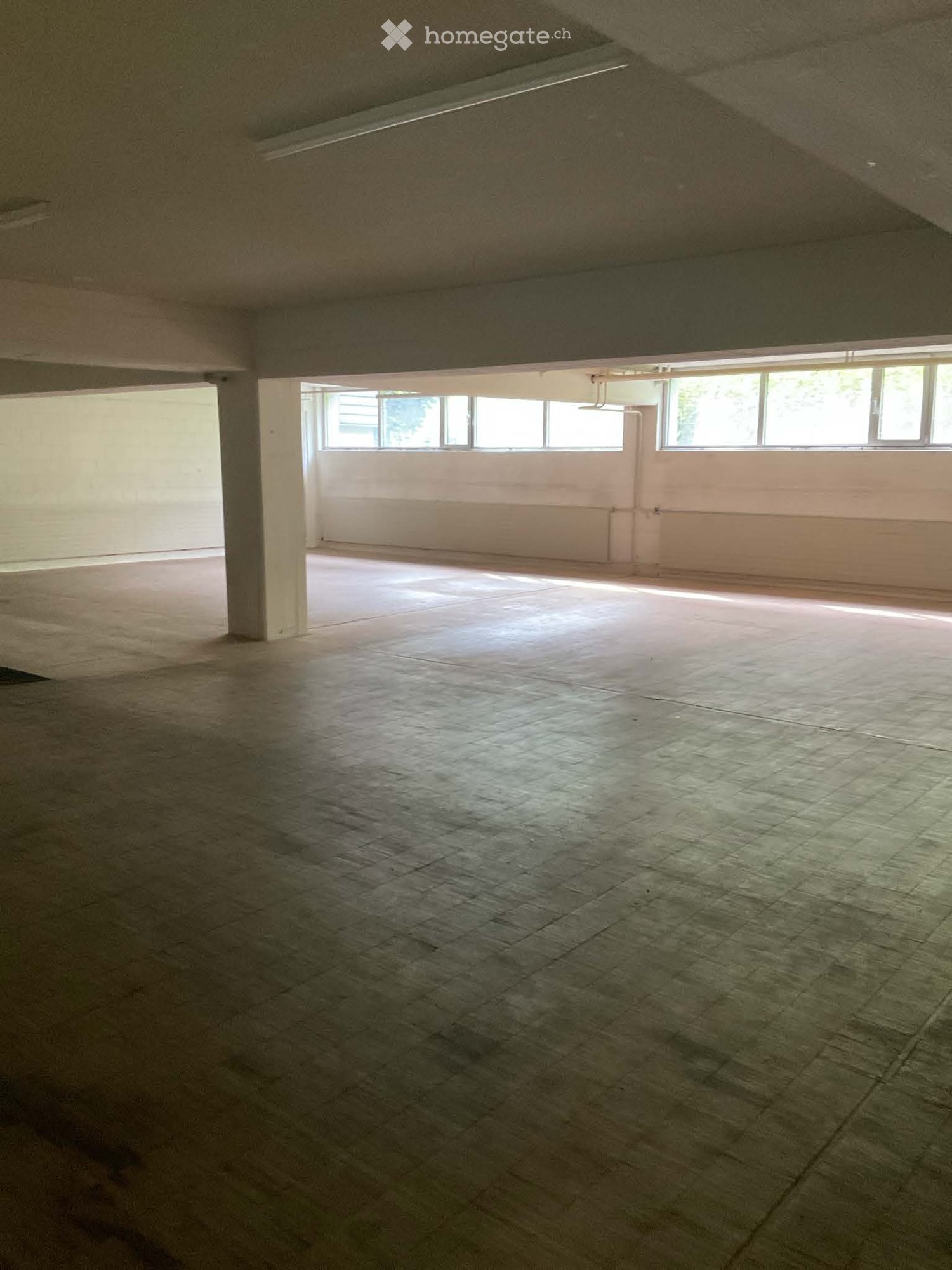 Unfurnished Room. Empty room with concrete floor, white walls, and large windows allowing natural light. No furniture or equipment present.
