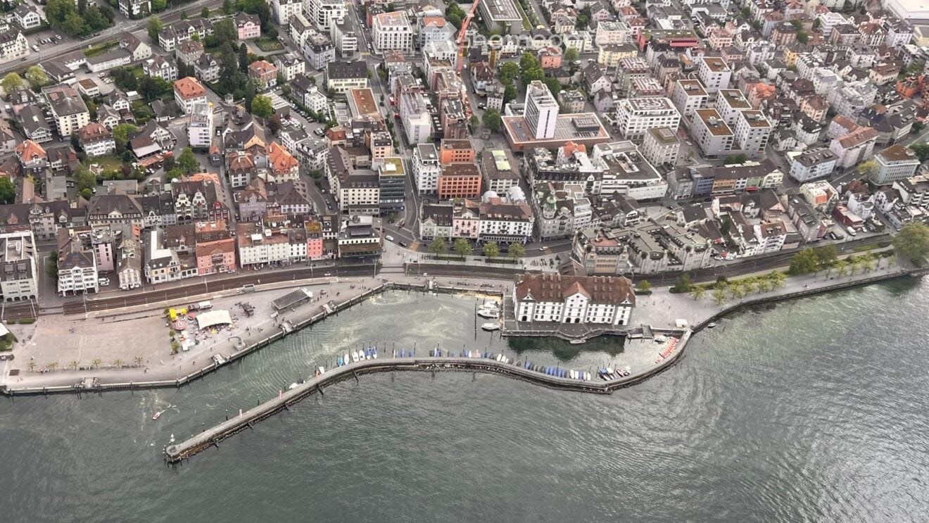 Building. Aerial view of a cityscape with numerous buildings, a waterfront area, and a pier extending into the water.