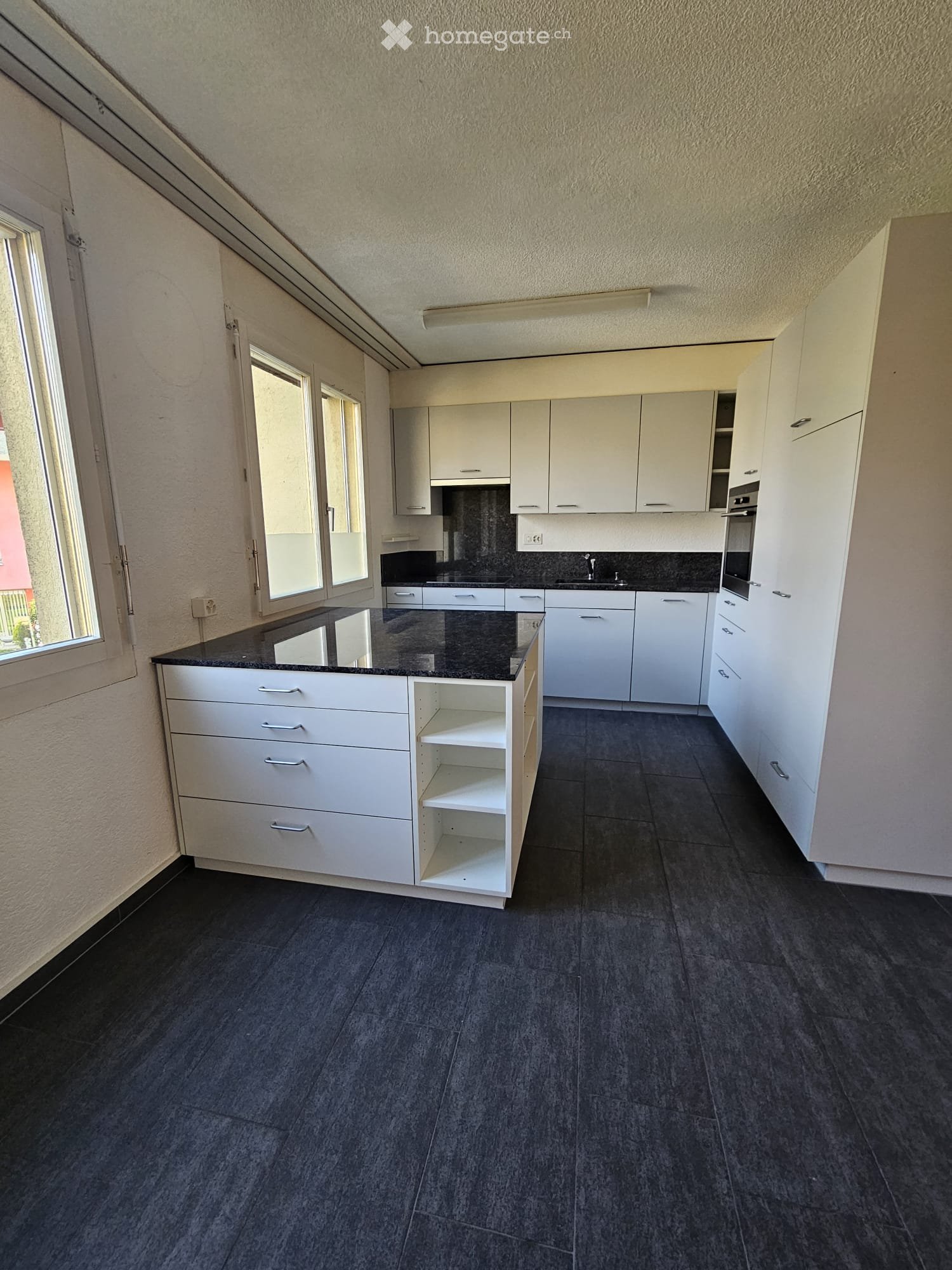 modern kitchen with white cabinets, black countertops, white shelves, black flooring, windows