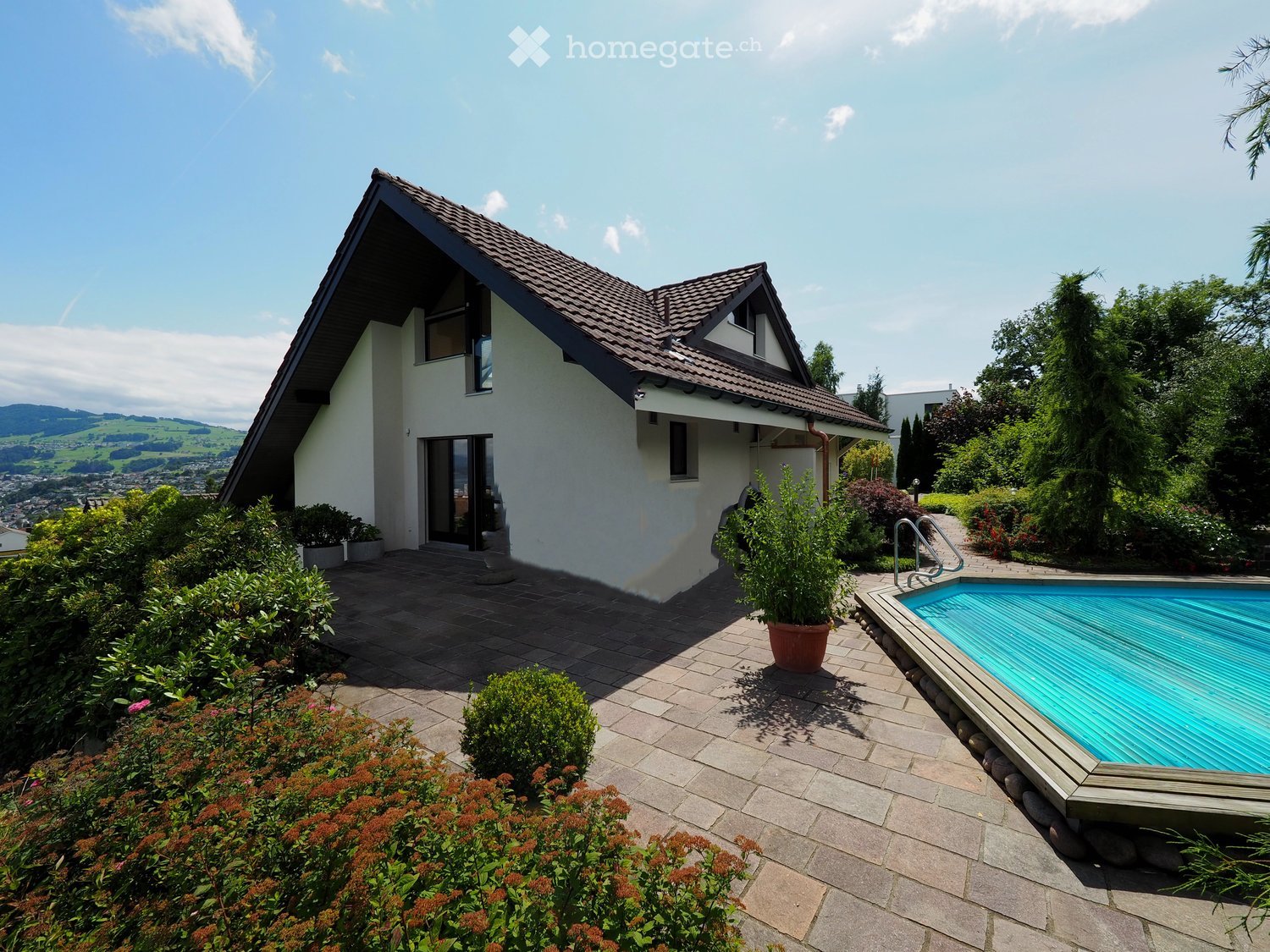 Garden / Outdoor Area. Modern house with a swimming pool, surrounded by well-maintained garden and plants, with a scenic view of the valley in the background.