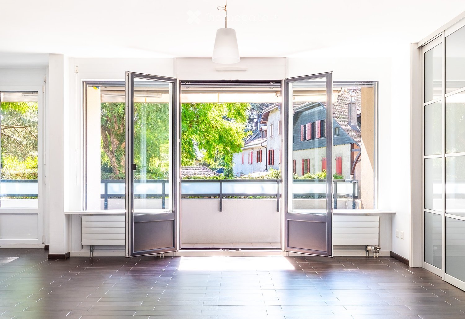 Unfurnished Room. Empty room with large sliding glass doors leading to a balcony, wooden flooring, white walls, and radiators.