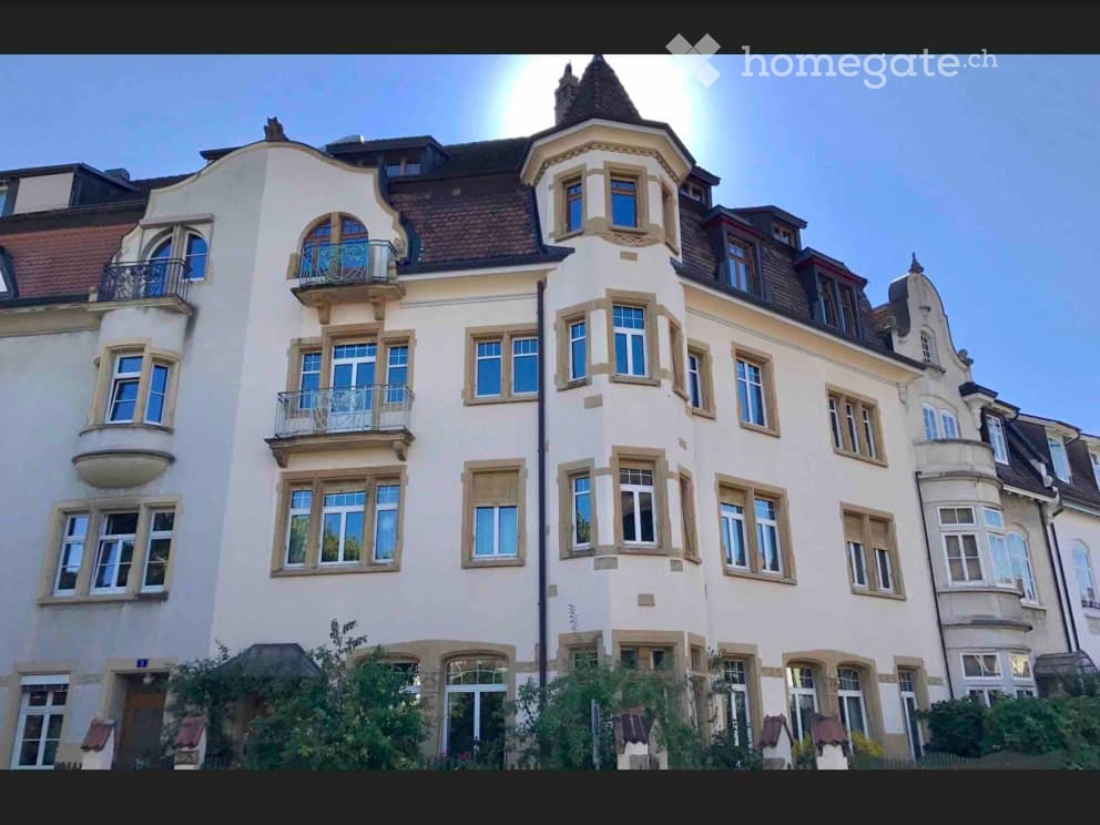 A multi-story residential building with a classic architectural style, featuring arched windows, balconies, and a decorative roofline.