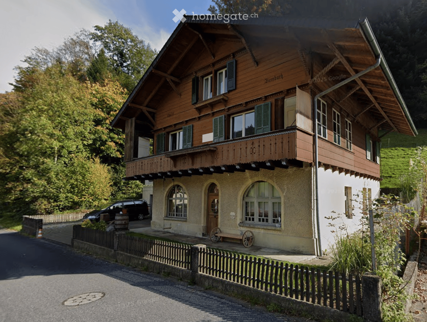 Alpine house, 3 story house, wooden exterior, balcony, car parked in front, wooden fence, trees