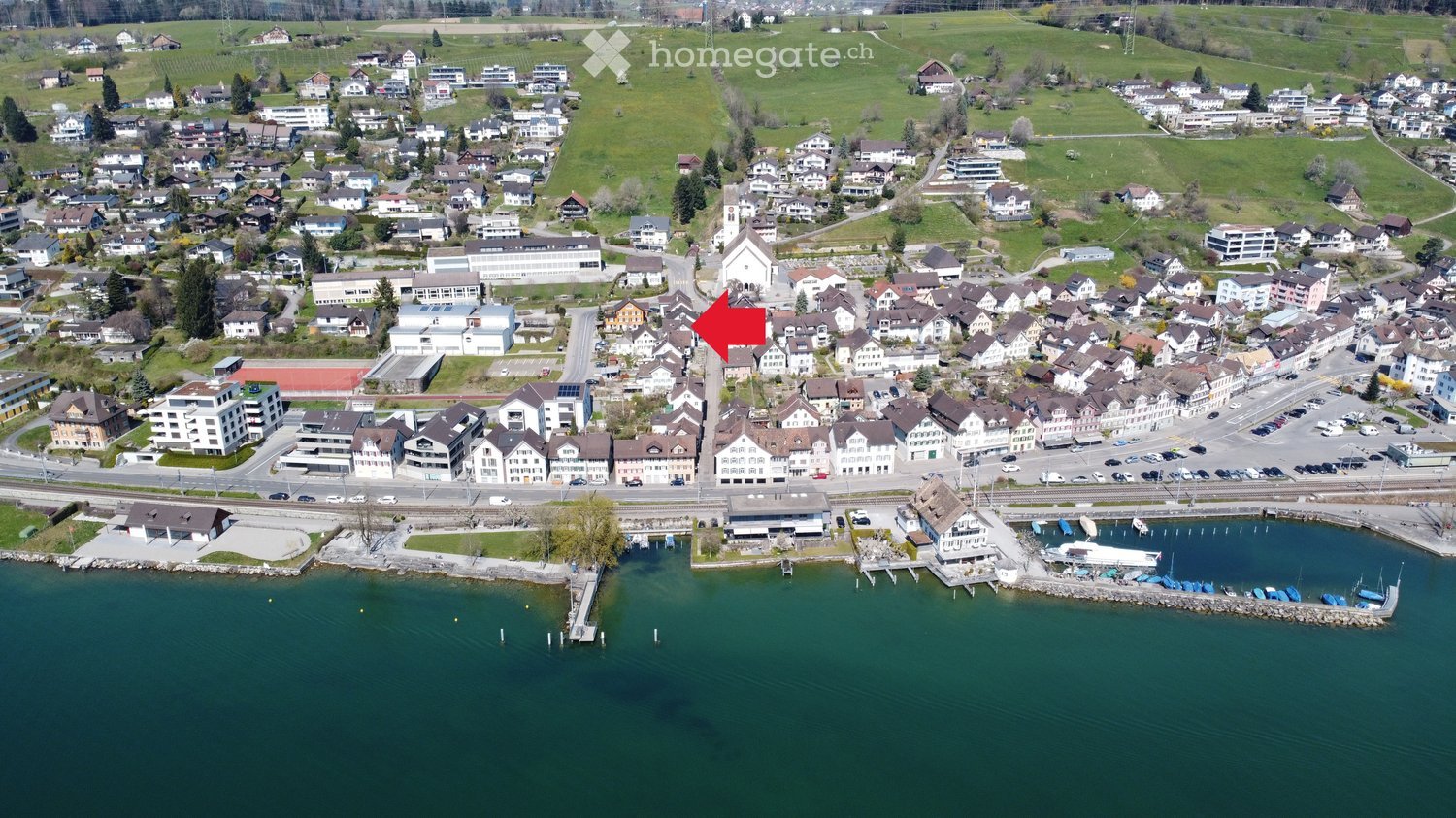 Building. Aerial view of a small town with houses, a church, a harbor, and a lake in the foreground.