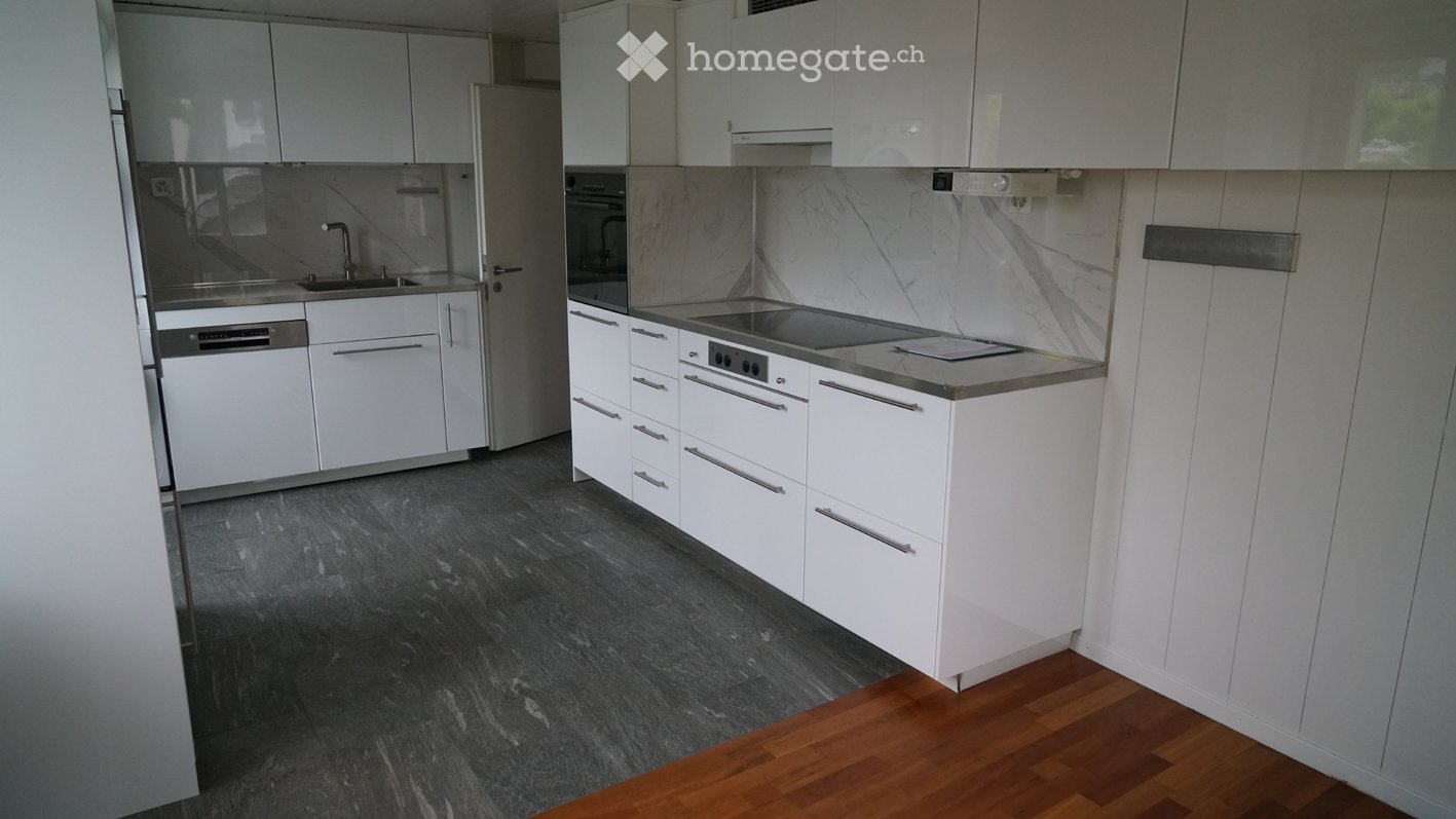 Modern kitchen with white cabinets, stainless steel appliances, marble backsplash, and dark grey tiled floor.