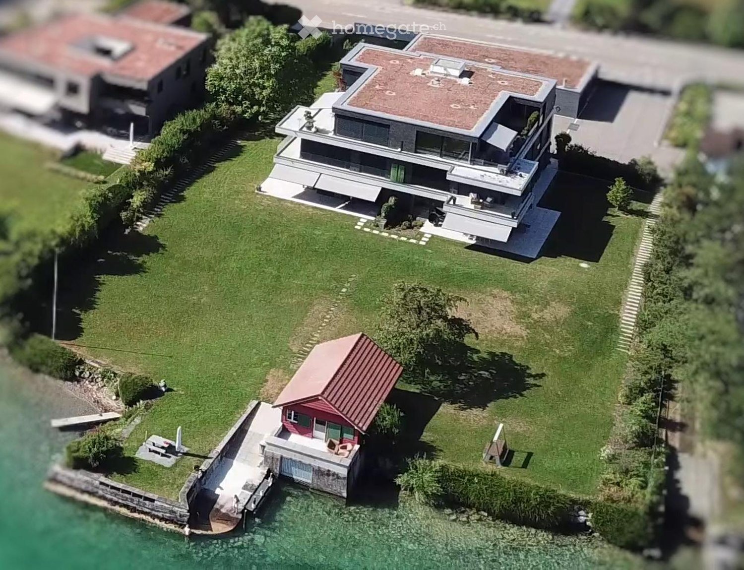 Modern house with 3 floors, red roof, large windows, garden, dock, lake view