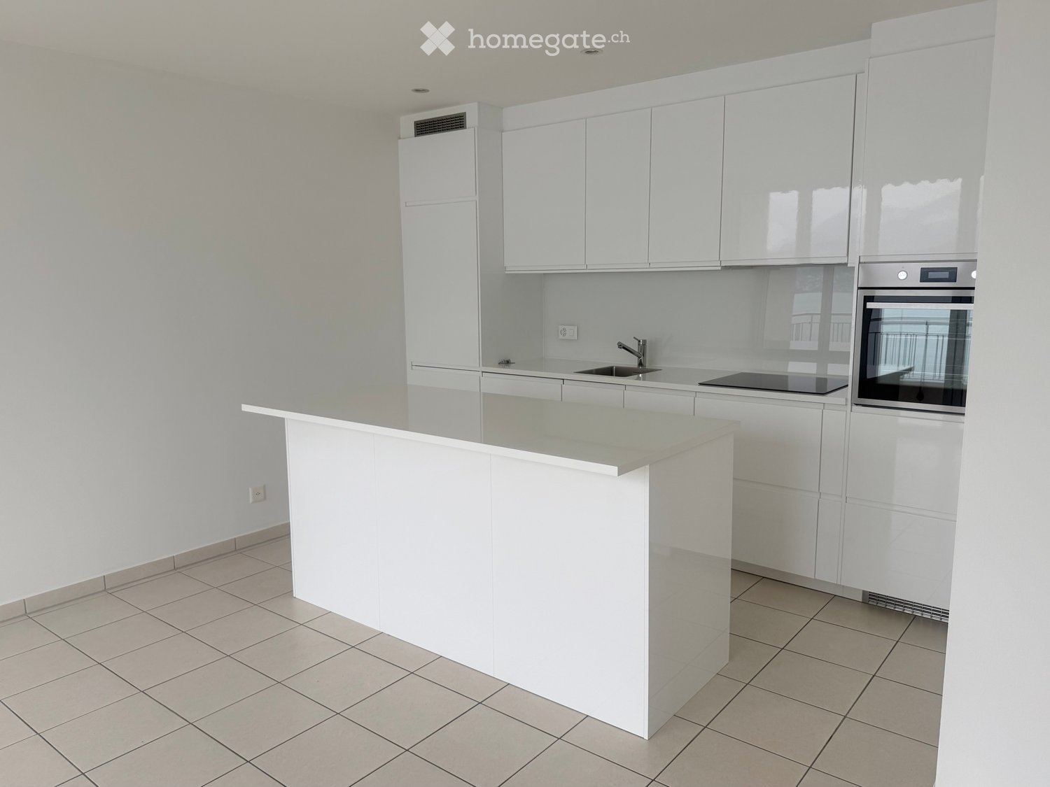 Modern kitchen with white cabinets, a central island, and built-in appliances including a sink, faucet, and oven.