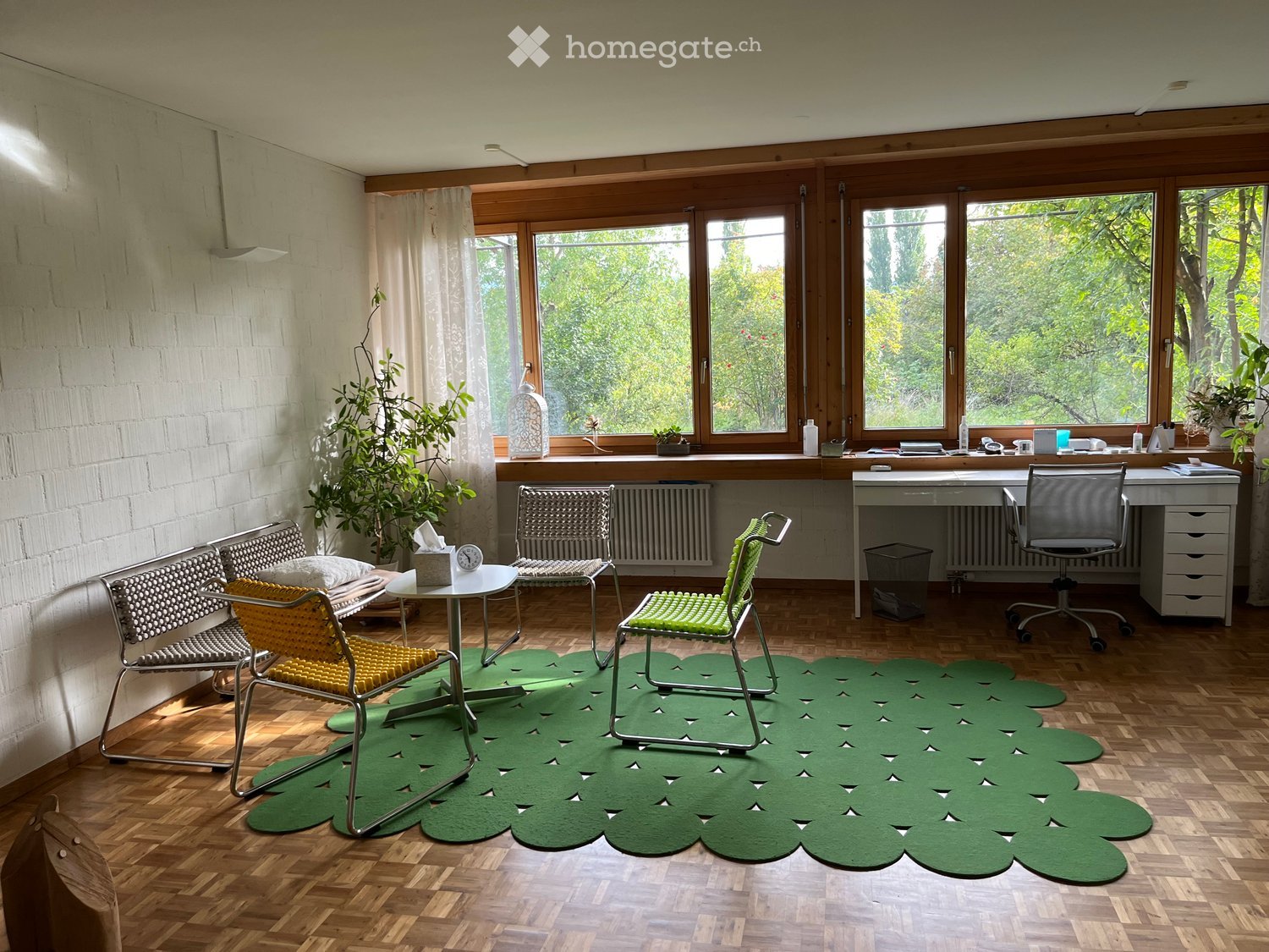 wood floor, three chairs around a table, round rug, desk, wooden desk, window with curtains