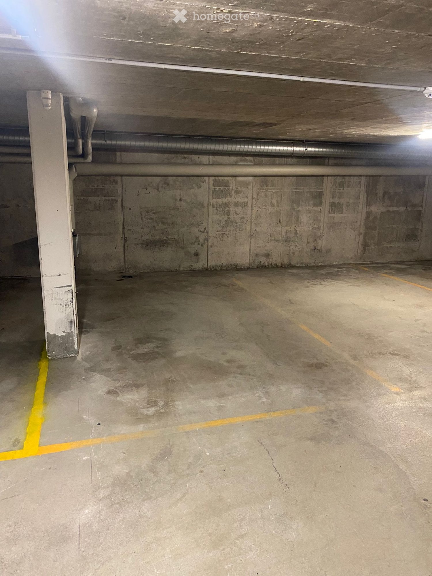 Other. Empty underground parking space with concrete floors and walls, marked parking spots, and visible pipes and structural elements.