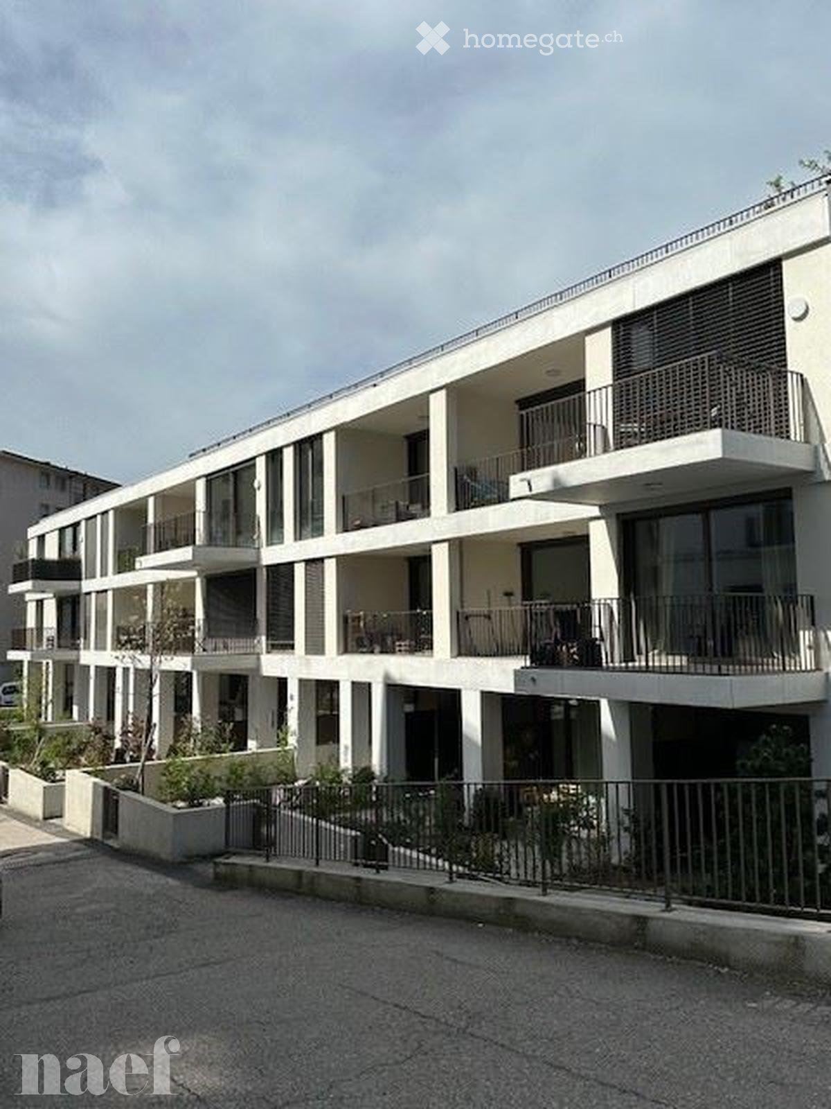 Building. Modern multi-story residential building with balconies, large windows, and a clean, contemporary design.