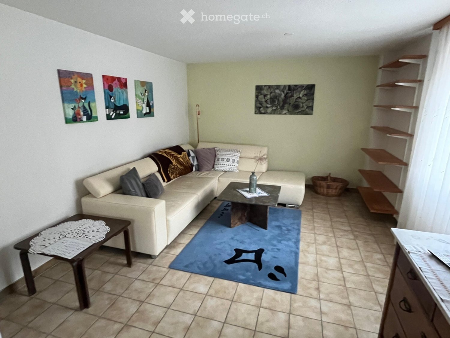 Living Room. Living room with a beige sectional sofa, coffee table, side table, shelves, and a blue rug.