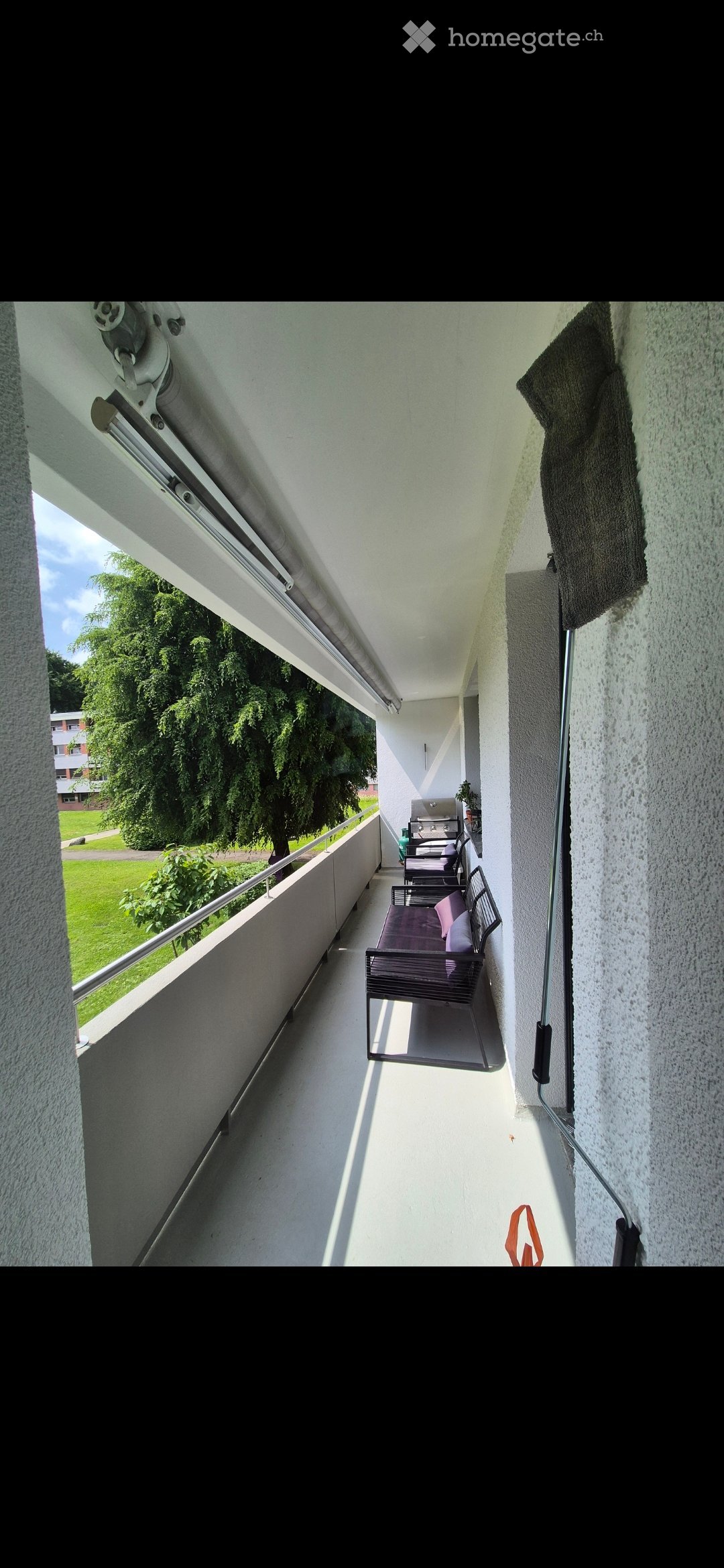 Balcony / Terrace. Balcony with a bench, table, and a view of a green lawn and trees.