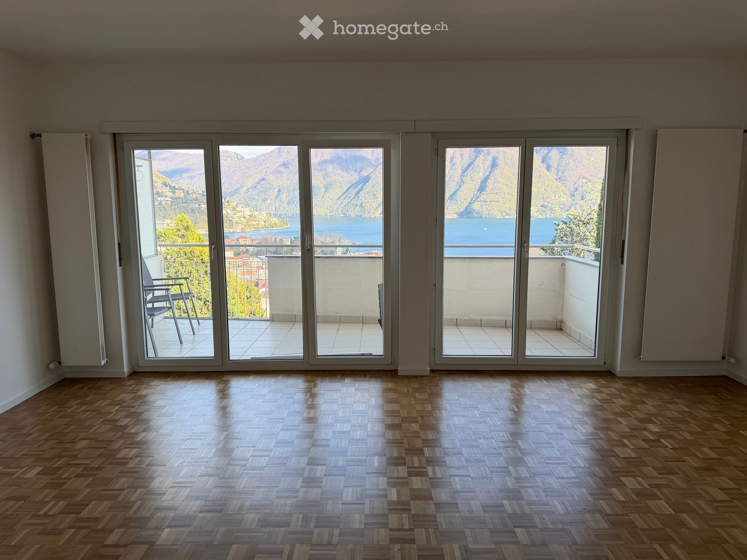 empty room, wooden parquet floor, large sliding glass doors, balcony, lake view
