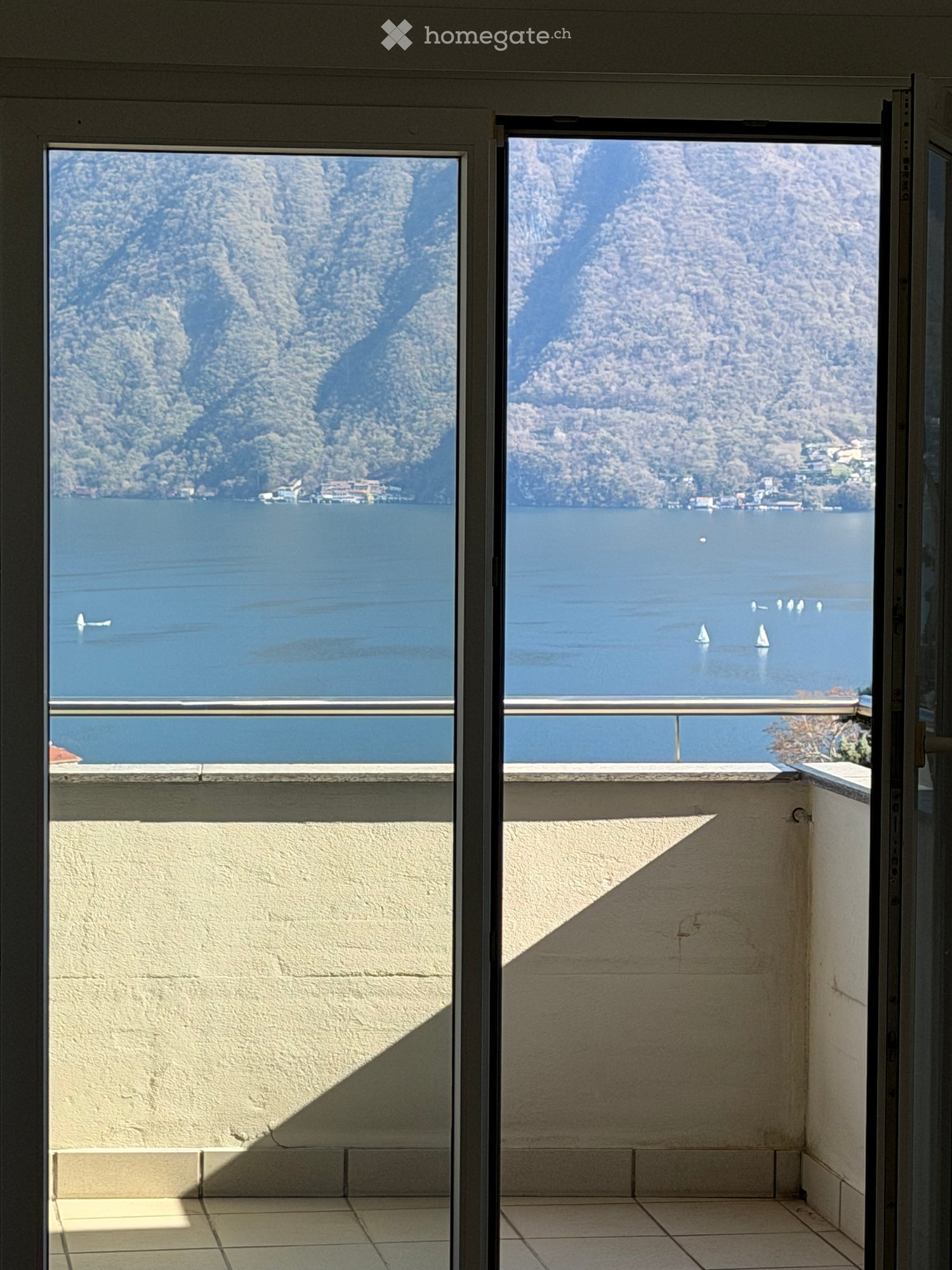 Balcony with lake view, tiled floor, sliding glass door, metal railing