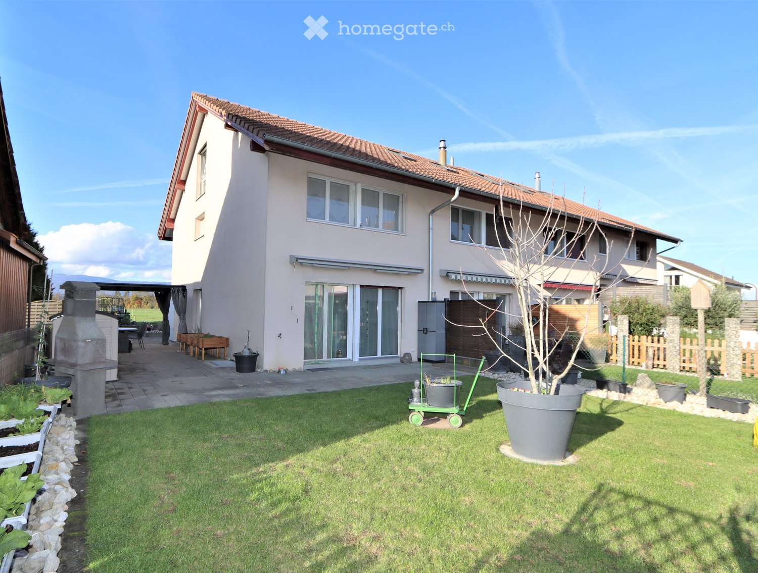 Garden / Outdoor Area. Well-maintained garden with a lawn, potted plants, a barbecue area, and a patio with outdoor furniture.