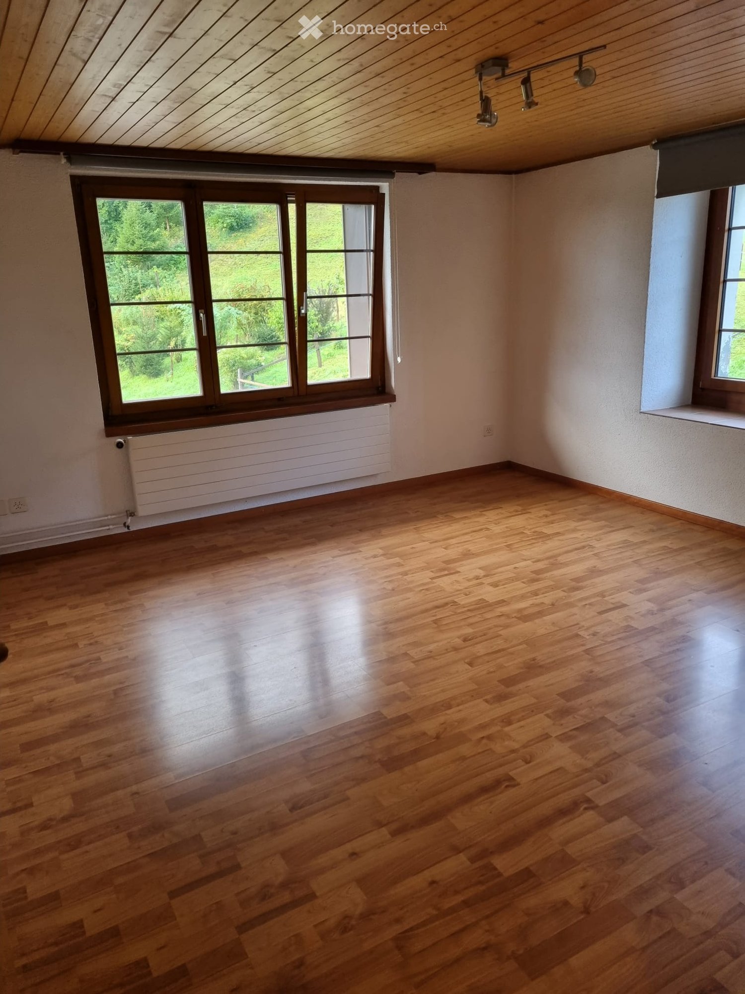 Unfurnished Room. Empty room with wooden flooring, large windows, radiator, and exposed wooden ceiling beams.