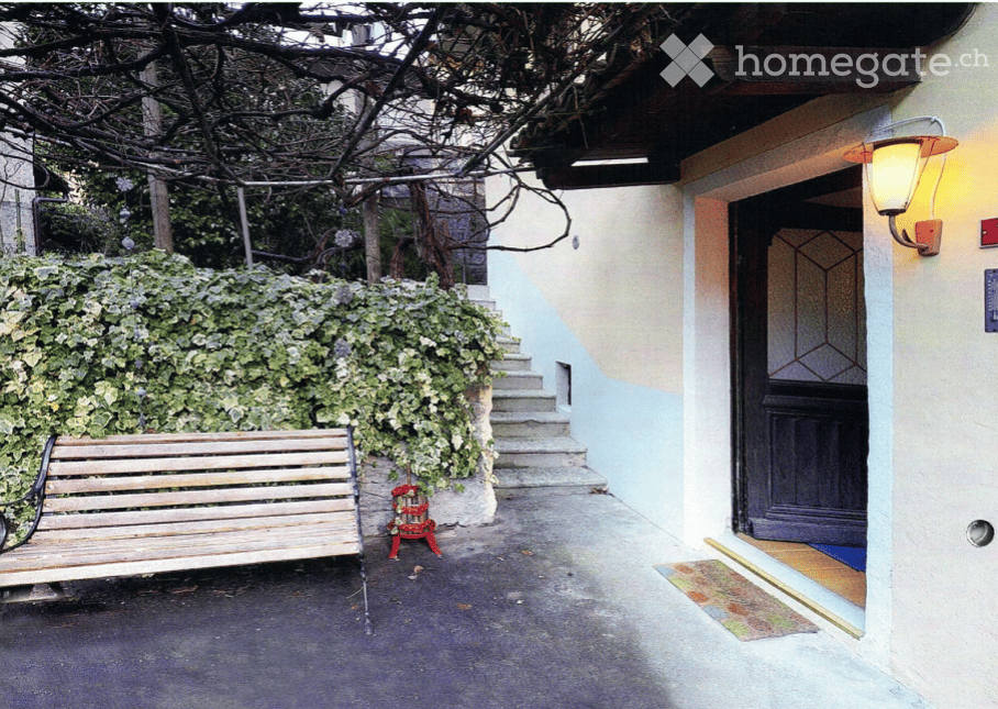 Garden / Outdoor Area. A raised entrance pathway leads to a building with a wooden bench and a small flower pot nearby.
