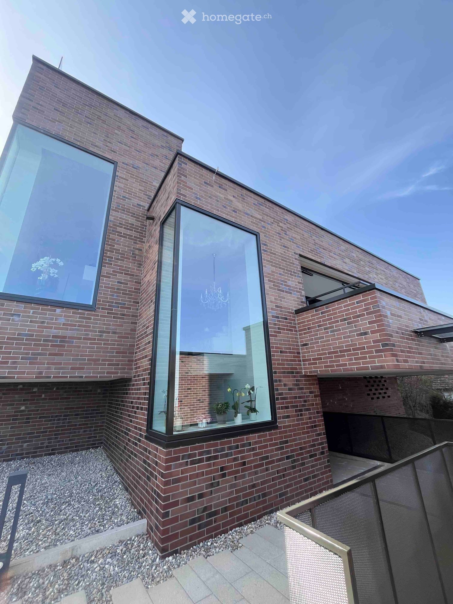 modern brick house, large glass windows, balcony, gravel pathway