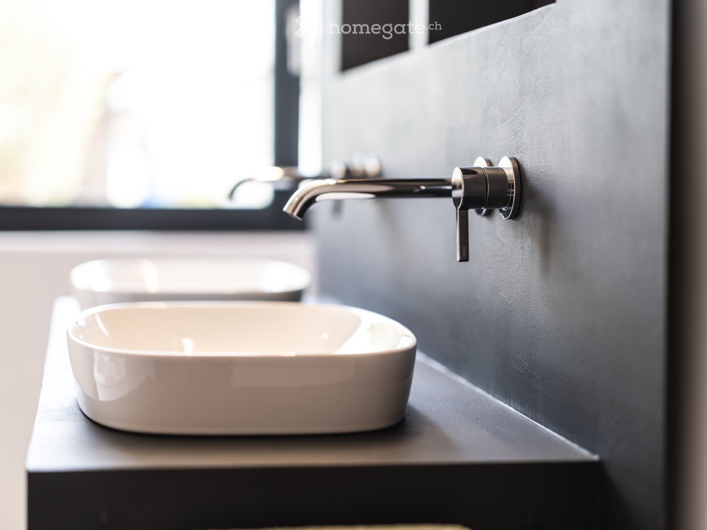 Bathroom. Modern bathroom with a sleek, minimalist design featuring a white sink and a contemporary chrome faucet mounted on a dark grey wall.