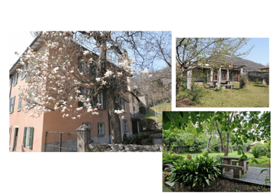 House. A two-story brick house with white shutters and a stone fence, surrounded by blooming trees and greenery. The property includes a patio area with outdoor furniture and a well-maintained garden.