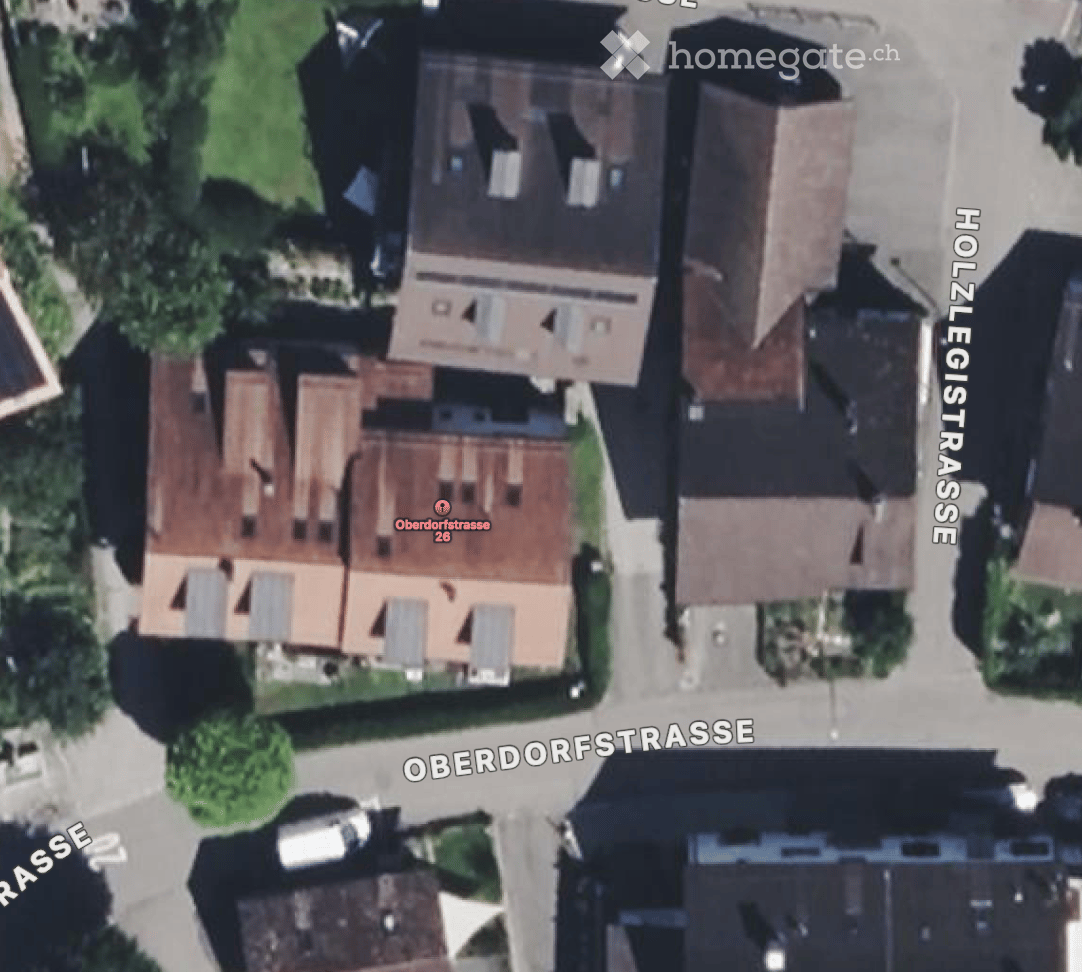 Building. Aerial view of a residential area showing multiple houses with pitched roofs and surrounding greenery.
