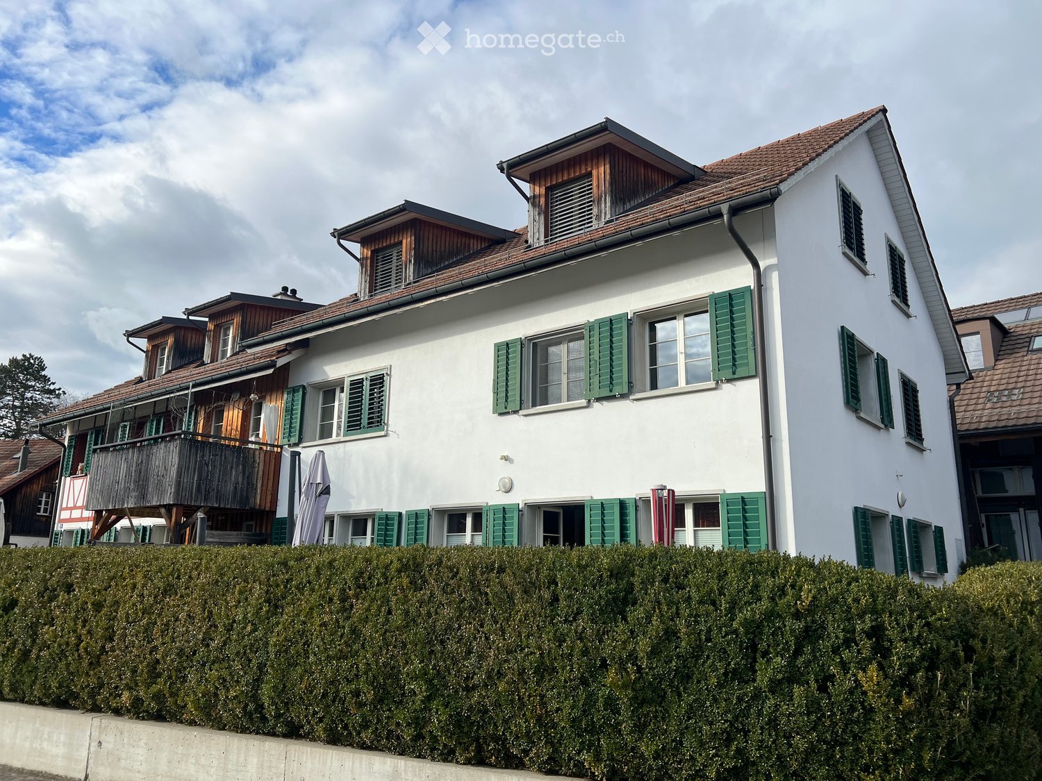 white house, brown roof, green shutters, balcony, hedge